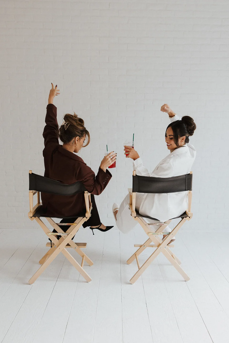 Stylist and client celebrate together from makeup chairs in a bright studio